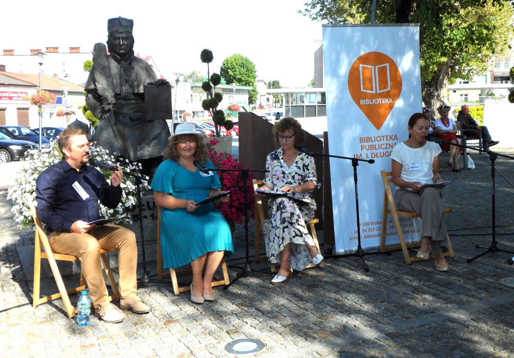 Miejsce plenerowe w Kłobucku. Na krzesłach cztery osoby czytające książki